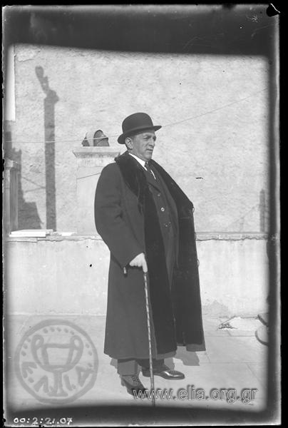 Man on a flat roof in a long coat and fur collar