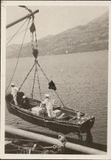 Tender, with two sailors, being lowered into the water from large boat