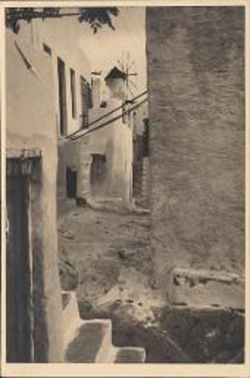 Myconos. Narrow pared street with windmill in the background