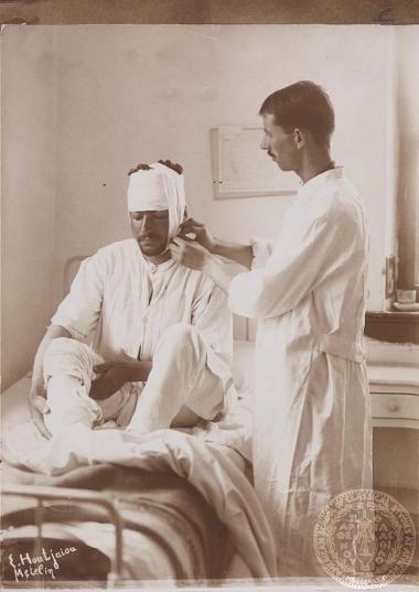 Ιατρός περιποιείται νεαρό άνδρα (πιθανότατα στρατιώτη) τραυματισμένο στο κεφάλι.