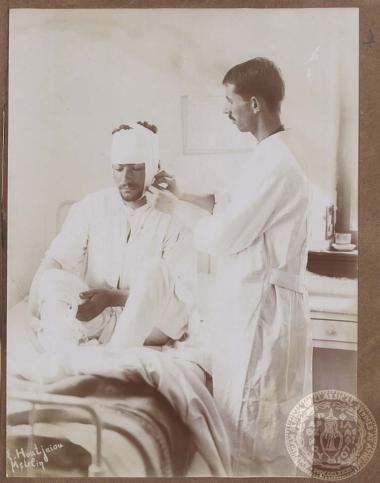 Ιατρός περιποιείται νεαρό άνδρα (πιθανότατα στρατιώτη) τραυματισμένο στο κεφάλι.