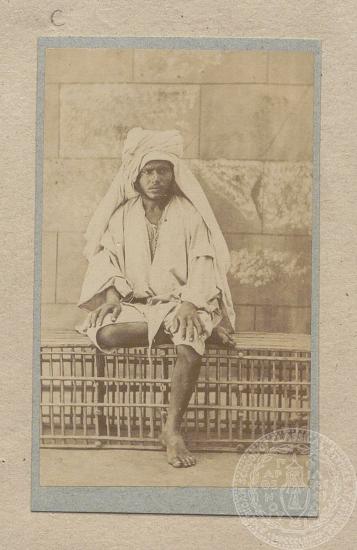 Φωτογραφία άντρα πιθανότατα κατώτερης κοινωνικής τάξης στην Αίγυπτο, ο οποίος κάθεται με σταυρωμένο το πόδι.