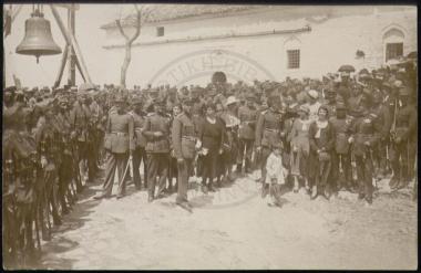 Εικονίζεται τμήμα του ελληνικού στρατού μετά πλήθους αξιωματικών και γηγενούς πληθυσμού με γιορτινή περιβολή