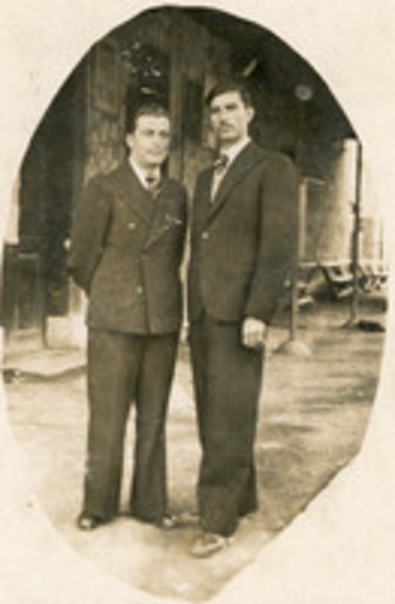 Δύο άνδρες με φόντο κτήριο σιδηροδρομικού σταθμού