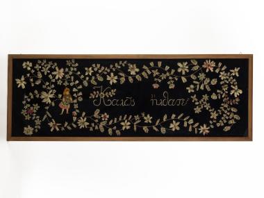 FRAMED EMBROIDERY THAT READS “WELCOME”