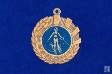 Αναμνηστικό μετάλλιο με κρίκο ανάρτησης και παράσταση αθλήτριας θαλάσσιου σκι σε μπλε σμάλτο