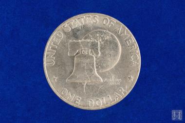 Αργυρό αναμνηστικό νόμισμα  με προτομή στην εμπρόσθια όψη και επιγραφή LIBERTY IN GOD WE TRUST 1776-1976 και στην οπίσθια, UNITED STATES OF AMERICA, ONE DOLAR