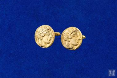 Δύο αργυρά μανικετόκουμπα (φέρουν χτύπημα 800 και 353) επιχρυσωμένα, με παράσταση αρχαίου νομίσματος.