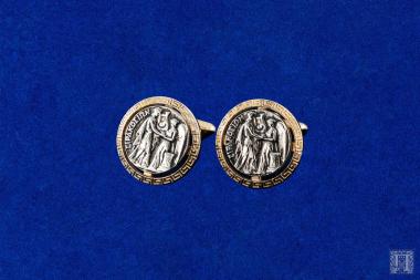 Δύο μανικετόκουμπα με παράσταση αρχαίου αργυρού νομίσματος που φέρουν την επιγραφή ΣΙΡΑΚΟΣΙΩΝ κολλημένα σε βάση από κράμα χαλκού.