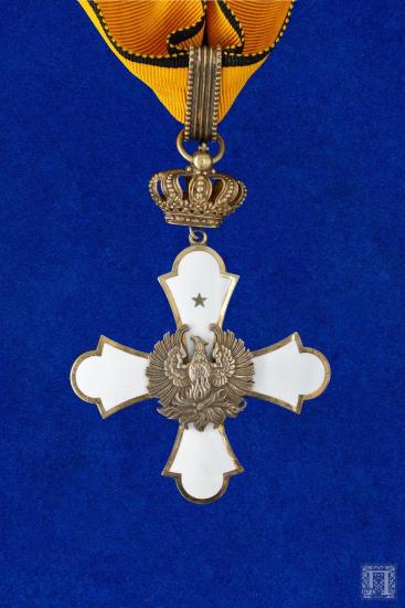 Μεγαλόσταυρος με κίτρινη γκρο κορδέλα, με διακόσμηση σε λευκό σμάλτο και κεντρικά στοιχεία στην εμπρόσθια όψη έναν Φοίνικα και στην οπίσθια, το μονόγραμμα Γ δύο φορές, διασταυρωμένο σα Χι (Γεώργιος ΙΙ) με το ΙΙ στο κάτω μέρος του και την κορώνα από πάνω του. Ανάμεσα στον σταυρό και την κορδέλα υπάρχει ως ενδιάμεσο συνδετικό διακοσμητικό μέσο, μία κορώνα από λευκό μέταλλο με μεγάλο κρίκο