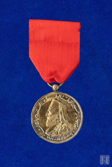 Μετάλλιο με  κόκκινη γκρο κορδέλα. Στην εμπρόσθια όψη απεικονίζεται ιεράρχης και υπάρχει επιγραφή στα αραβικά ενώ στην οπίσθια όψη γύρω από την παράσταση αναγράφεται JUBILE DOR DE S.B. LE PATRIARCHE ALEXANDRE III και στο κέντρο χαμηλά, DAMAS 1803-1954