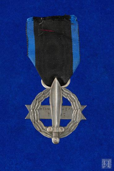 Μετάλλιο με μπλε γκρο κορδέλα. Στην εμπρόσθια όψη μέσα σε δάφνινο στεφάνι υπάρχει ένα σπαθί και η επιγραφή Η ΤΑΝ Η ΕΠΙ ΤΑΣ ενώ στην οπίσθια ΕΛΛΑΣ 1916-1917