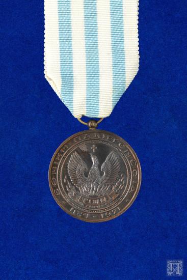 Μετάλλιο σε ριγέ λευκή και σιέλ γκρο κορδέλα με τη μονή της Αγίας Λαύρας στη μία όψη και την επιγραφή ΕΛΕΥΘΕΡΙΑ Ή ΘΑΝΑΤΟΣ 1821 και τον Φοίνικα με την επιγραφή ΤΙΜΗ, ΕΘΝΙΚΗ ΠΑΛΙΓΓΕΝΕΣΙΑ 1821-1971 στην άλλη