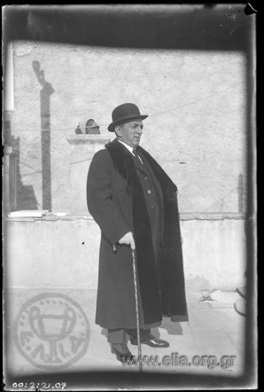 Man on a flat roof in a long coat and fur collar