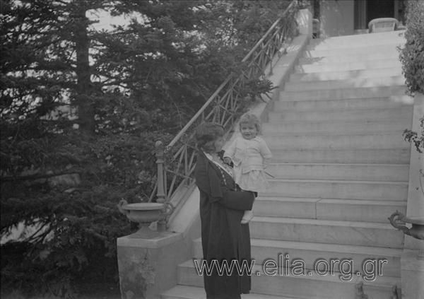 Woman with a child in her arms at a stairway of a villa