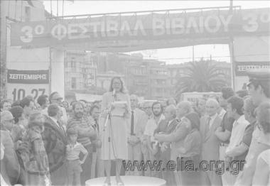 Εγκαίνια της τρίτης έκθεσης βιβλίου στο Πεδίον του Άρεως. Η υπουργός Πολιτισμού, Μελίνα Μερκούρη, εκφωνεί λόγο. Αριστερά διακρίνεται ο υφυπουργός Εμπορίου, Θεόδωρος Πάγκαλος. Πίσω από τη μελίνα Μερκούρη, ο υπουργός Εθνικής Παιδείας και Θρησκευμάτων, Απόστολος Κακλαμάνης.