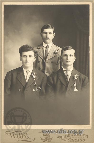 Ομαδικό πορτραίτο τριών ανδρών με μπουτονιέρες.