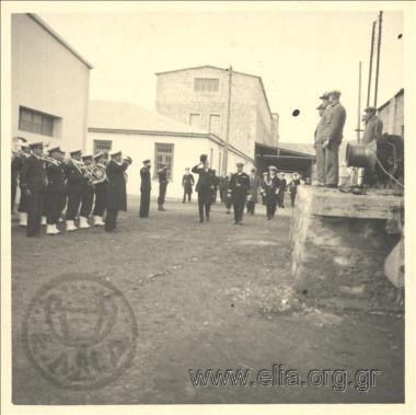 Ο Ιπποκράτης Παπαβασιλείου, υφυπουργός Ναυτικών, σε επίσημη επίσκεψη στο Ναύσταθμο. Η Μουσική ΠΝ, με αρχιμουσικό τον Σημαιοφόρο Σταύρο Καγκελάρη, αποδίδει τιμές.