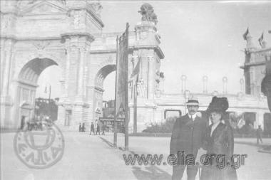 Ο Ιπποκράτης Παπαβασιλείου και μία γυναίκα ποζάρουν με φόντο πύλη κάποιας κεντροευρωπαϊκής πόλης.