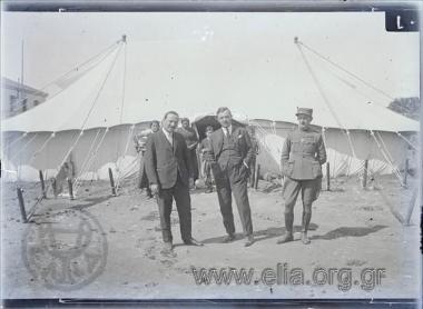 Μικρασιατική εκστρατεία, άνδρες και στρατιωτικός ποζάρουν μπροστά από σκηνή που στεγάζει πρόσφυγες.