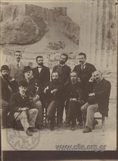 Ο κύκλος της Εστίας στο Ολυμπιείο. Πρόκειται για τη μισή από τη γνωστή φωτογραφία του κύκλου της Εστίας. Σε αυτό το τμήμα εικονίζονται από αριστερά καθιστοί:  Νικόλαος Πολίτης, Στέφανος Στεφάνου, Μιχαήλ (Μίκιος) Λάμπρος, Γεώργιος Σουρής, Εμμανουήλ Ροϊδης, Εμμανουήλ Λυκούδης. Όρθιοι από αριστερά: Γιάννης Βλαχογιάννης, Κωστής Παλαμάς, Γεώργιος Δροσίνης, Γρηγόριος Ξενόπουλος.