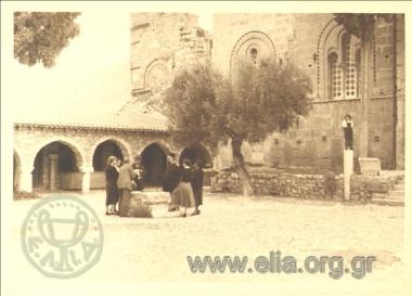 Visitors and a priest in a church courtyard