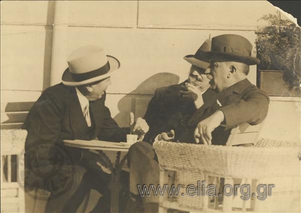 Panagis Tsaldaris discussing with two men in a café.
