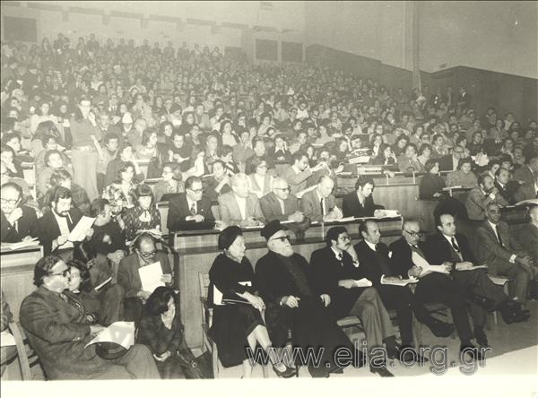 Assembly in a school amphitheater. We can see Amalia Fleming in the first row. At the back, on the left, Giorgos Gennimatas.