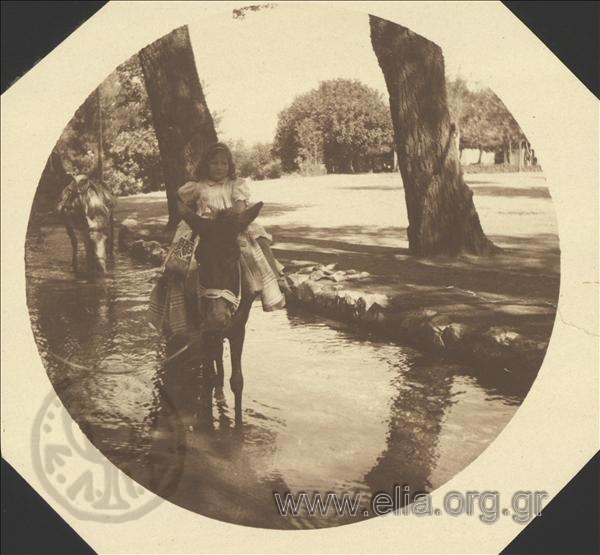 Hélène on a donkey by a river of a park.
