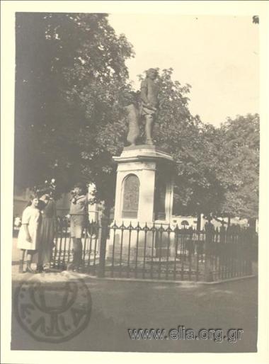 Ο Νικόλας Κάλας (1907-1988), παιδί, με κορίτσι και γυναίκα μπροστά απο άγαλμα σε πλατεία.