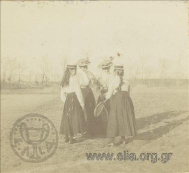 Four young women with tennis rackets at a park.