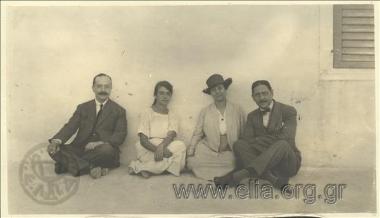 Δύο άνδρες και δύο γυναίκες καθιστοί σε αυλή.