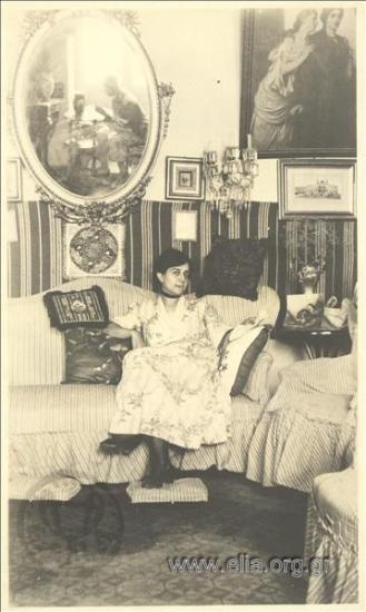 Portrait of a woman on a sofa. The photographer can be seen in the mirror behind her.