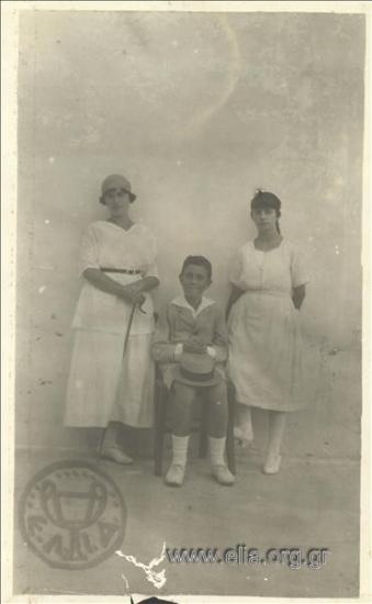 Αγόρι και δύο κορίτσια ποζάρουν σε βεράντα.