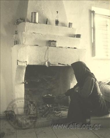 Ηλικιωμένη μαγειρεύει σε φούρνο χωριάτικου σπιτιού.