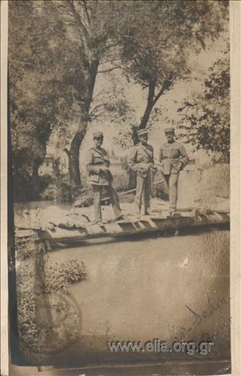 Portrait of three military officer s at a wooden bridge.