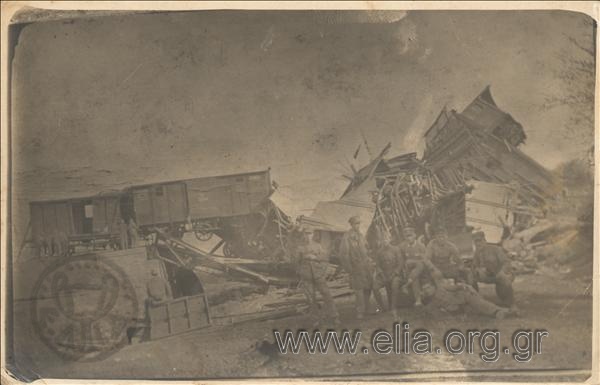Group portrait of soldiers in front of a destroyed bridge and a motor car.