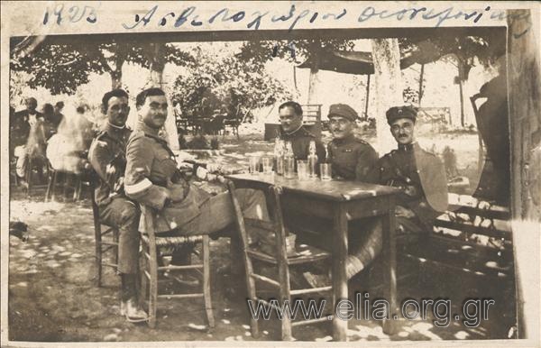 Group portrait of four officers and a petty officer of the Army in an outdoor coffeehouse.