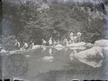 A group of friends in a setting with trees, rocks and water.