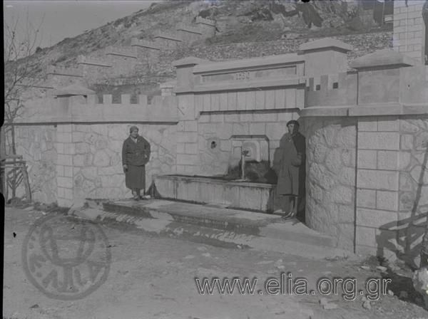 Η Ίρις μπροστά στο μαρμάρινο υδραγωγείο της Ζωοδόχου Πηγής με ανάγλυφη χρονολογία 1930.