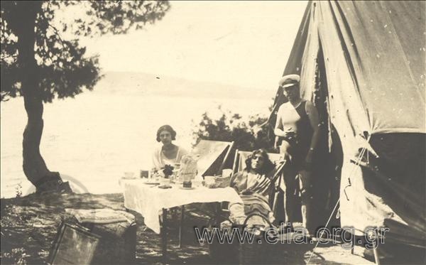 Ο Γεράσιμος Β. Βασιλειάδης και δύο γυναίκες αναπαύονται σε κατασκήνωση δίπλα στη θάλασσα.