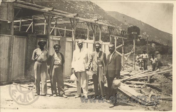 Gerasimos V. Vasiliadis in front of a destroyed wooden building