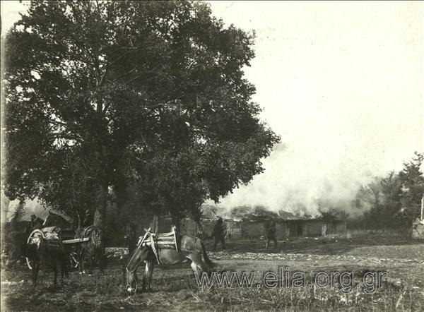 Soldiers next to a burning farmhouse.