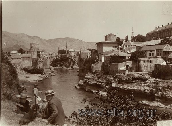 Η Παλαιά γέφυρα του Mostar και ο ποταμός Neretva. Στο βάθος διακρίνεται το τζαμί Koski Mehmed-Pasha, στην αριστερή όχθη του ποταμού. Η γέφυρα χτίστηκε το 1566 από τον αρχιτέκτονα Hajrudin.