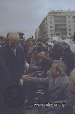 Εορτασμός της 25ης Μαρτίου: ο Πρόεδρος της Δημοκρατίας, Κωνσταντίνος Καραμανλής, χαιρετά ανάπηρους πολέμου.