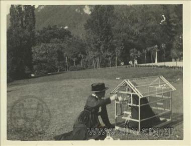 Μία από τις θείες του Νικόλαου Τομπάζη ταίζει νεαρός άνδρας που βρίσκεται μέσα σε κλουβί ωδικών πτηνών.