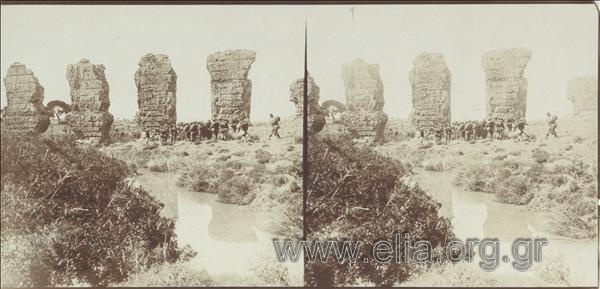 Infantry corps gathered next to Roman aquaduct, outdoor military drills.