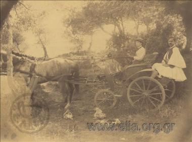 Lady driving a cart, a man in foustanela (Greek  kilt) escorts her.
