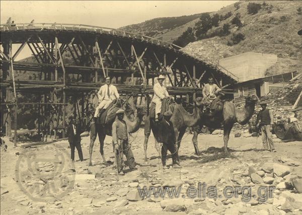 Κατασκευή γέφυρας στον ποταμό Νέστο. Οι εργολάβοι του έργου(;) ποζάρουν πάνω σε καμήλες μεάσα στην κοίτη του ποταμού με φόντο τη γέφυρα.