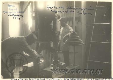 Ο αρχιτεχνίτης του μηχανουργείου Καλοχαιρέτα της Σμύρνης επιβλέπει στρατιώτη που χειρίζεται μηχάνημα σε εργαστήριο παρασκευής μακαρονιών για τον ελληνικό στρατό σε χώρο όπου παλαιότερα στεγαζόταν αρμένικος κινηματογράφος. Μικρασιατική εκστρατεία.